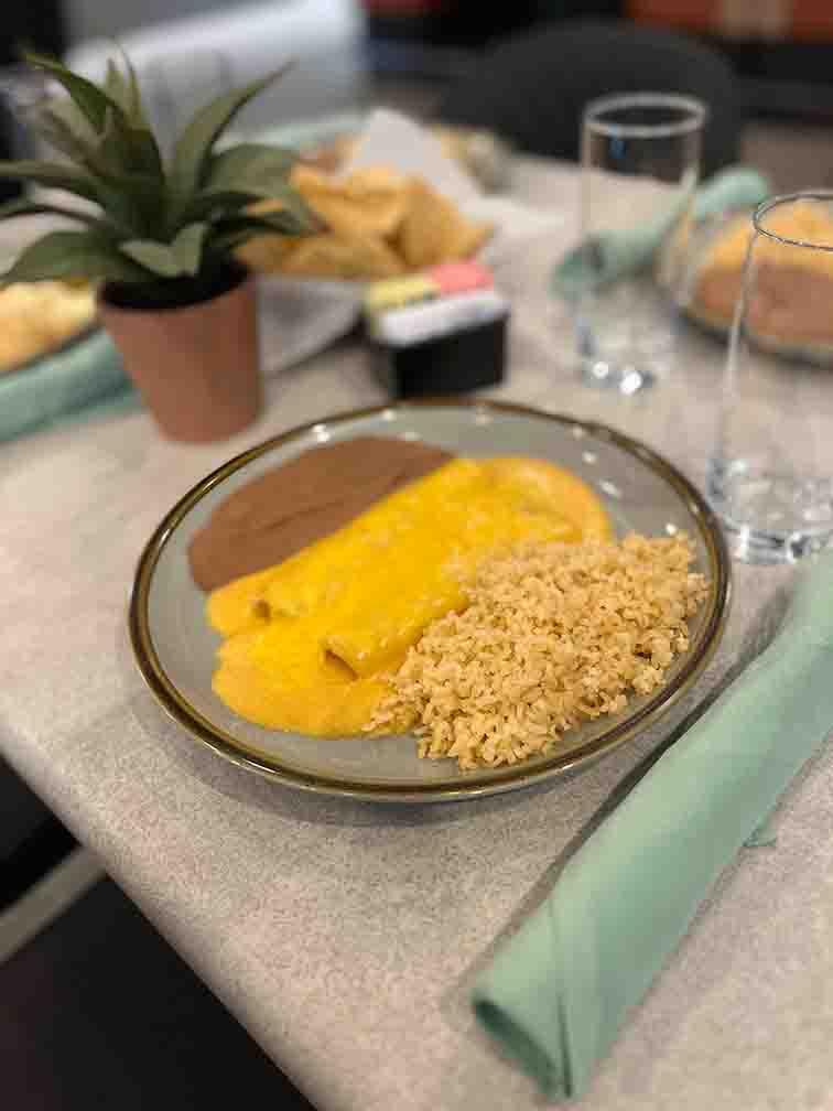 Number 10 plate with two cheese enchiladas topped with melted Queso, served with Mexican rice and refried beans, a cheesy Tex-Mex favorite at Tequileros restaurant in Frisco, Collin County, Texas.